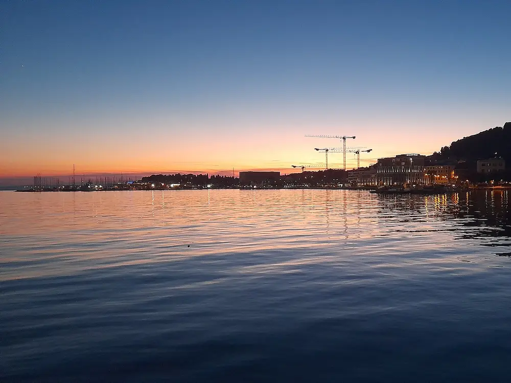 Abenddämmerung über dem Hafen, die Lichter der Stadt gehen an
